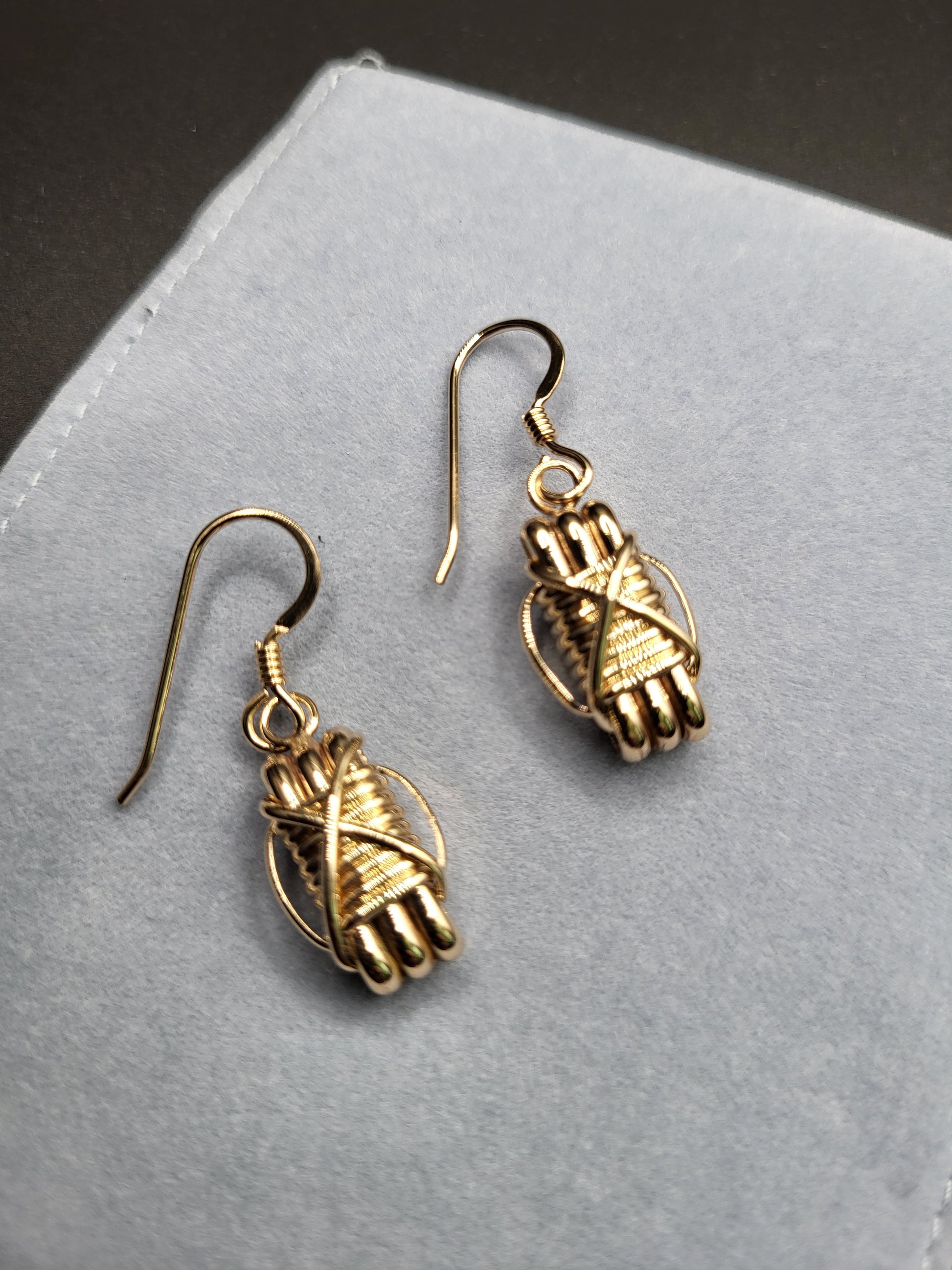 Elephant Hair Gold Dangle Earrings On Light Background